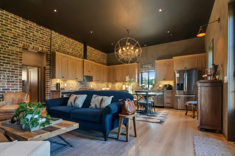 Open-concept living room and kitchen with exposed brick and a chandelier