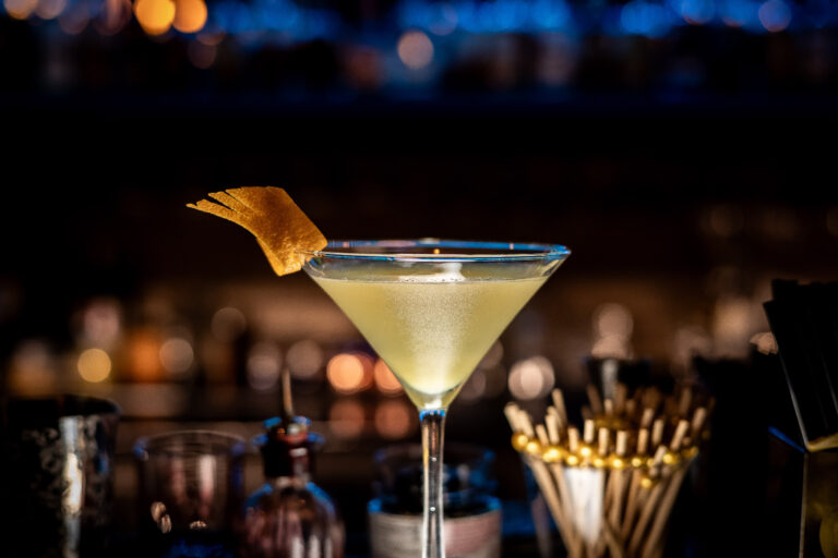 Craft cocktail styled on a bar top with warm bokeh lighting