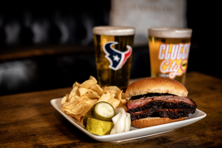 Barbecue brisket sandwich with chips and Houston Texans drink cups
