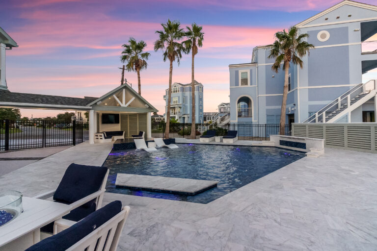 Resort-style backyard pool and spa at dusk framed by palm trees